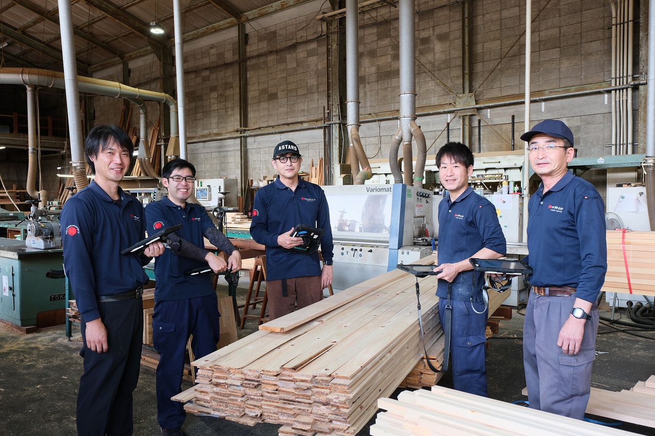 木材の前で談笑する5人の男性作業員